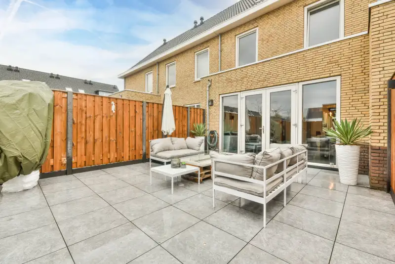 Achtertuin met lichte sierbestrating en loungeset