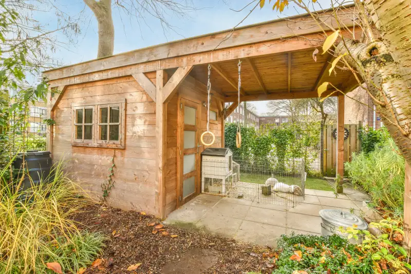 Houten tuinhuis met overkapping in verzorgde tuin