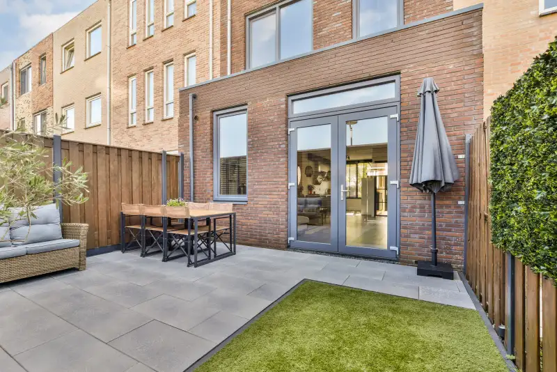 Compact aangelegde stadstuin met terras, kunstgras en loungeset