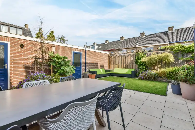 Verzorgde achtertuin met terras, gazon, loungeset en beplante borders