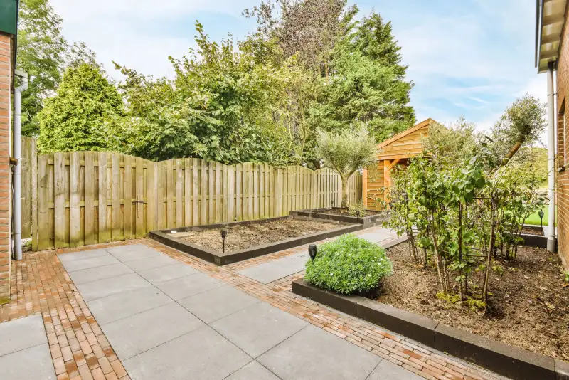 Vernieuwde achtertuin met antraciet tegels, klinkerpad en borders met beplanting